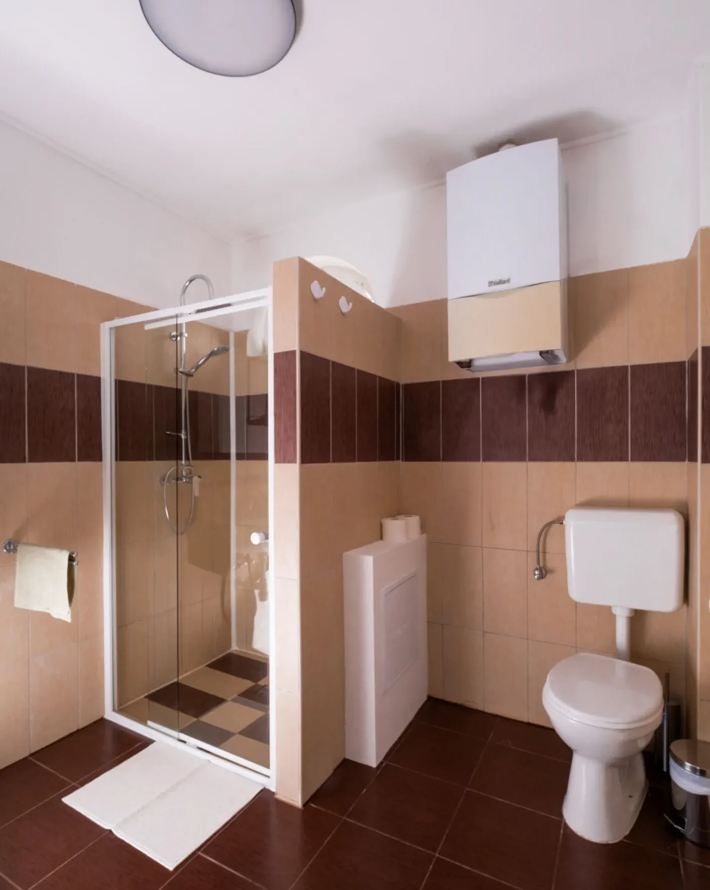 modern fürdőszoba barna csempével bojlerrel zuhanykabinnal és wc-vel