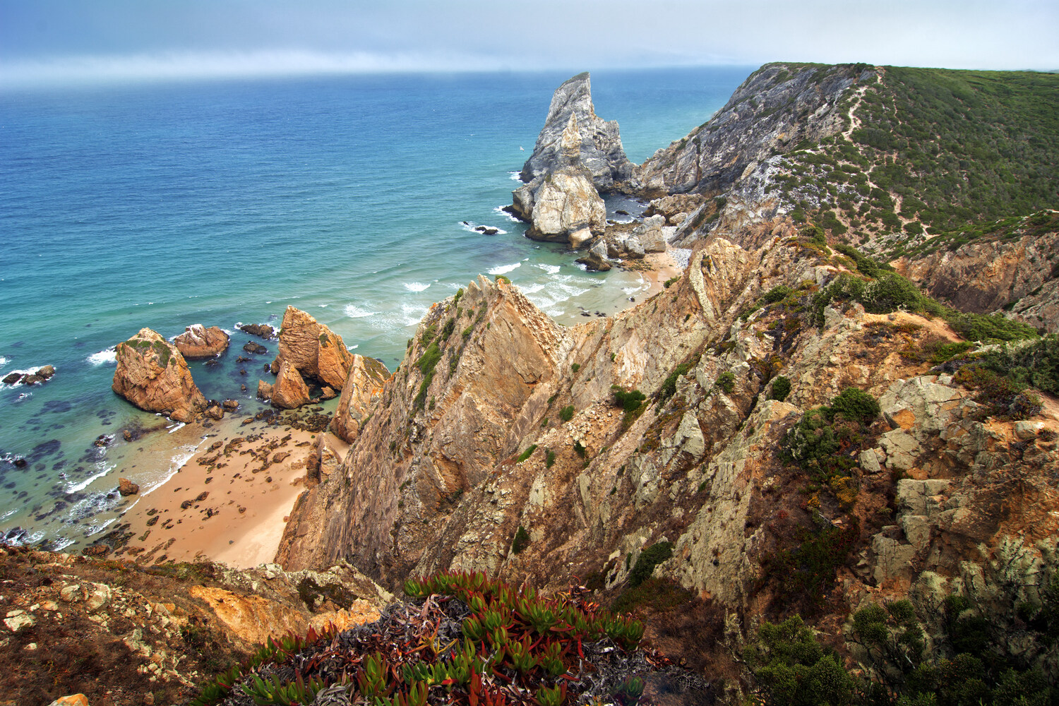Hatalmas sziklák és az Atlanti-óceán partvidéke a portugáliai Praia da Ursa strandon, Cabo da Roca közelében